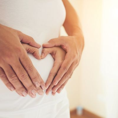 Pregnant Woman and Her Husband hand showing heart shape.